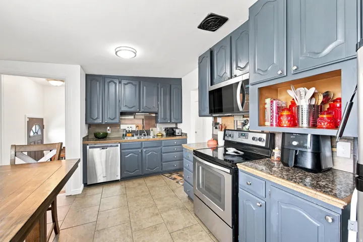 Kitchen featuring blue cabinetry, stainless steel appliances, and tiled flooring