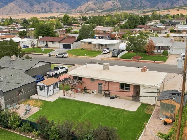 Expansive backyard featuring a manicured lawn, concrete patio, and built-in storage shed