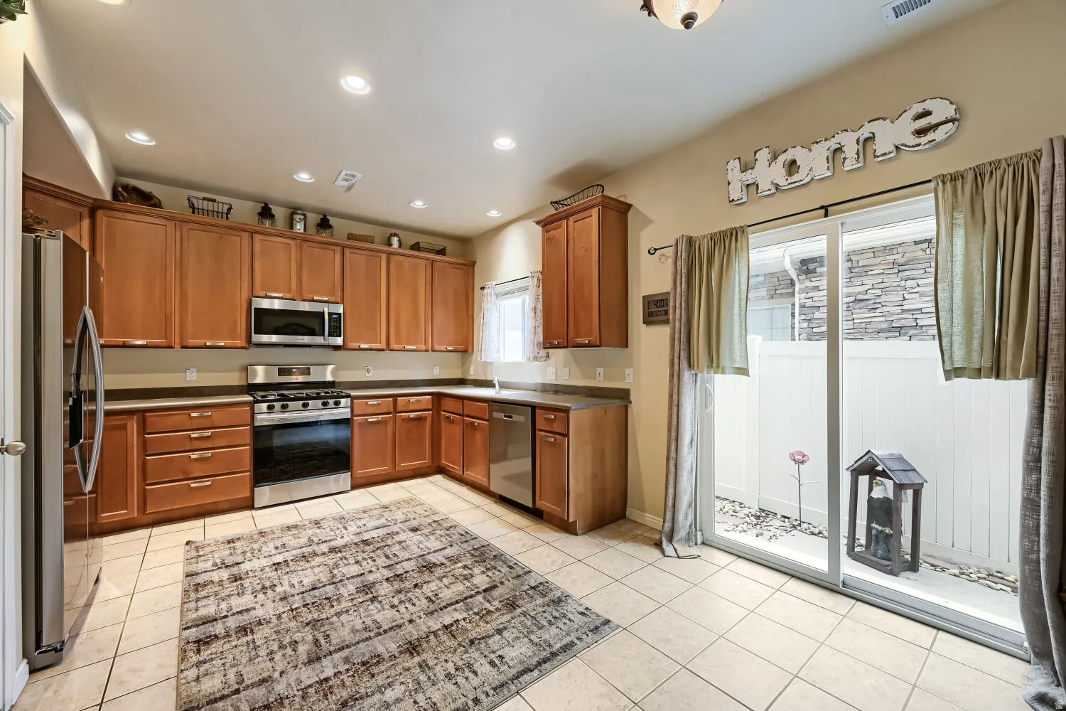 Kitchen with recessed lighting, wood-finish cabinetry, stainless steel appliances, and a sliding glass door