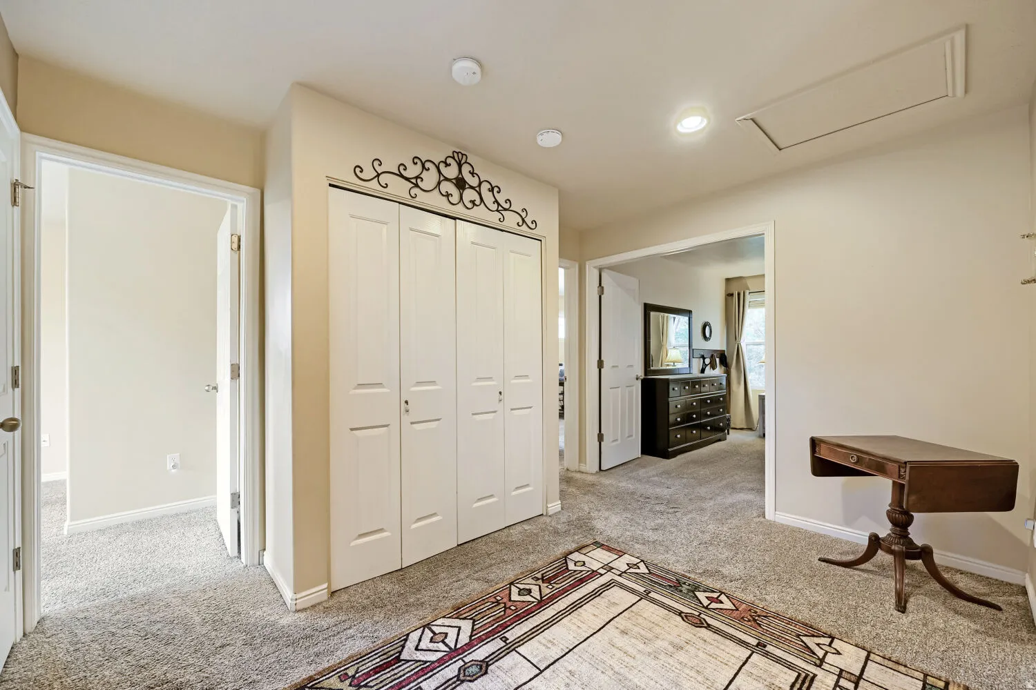 Carpeted hallway with a built-in closet featuring bi-fold doors