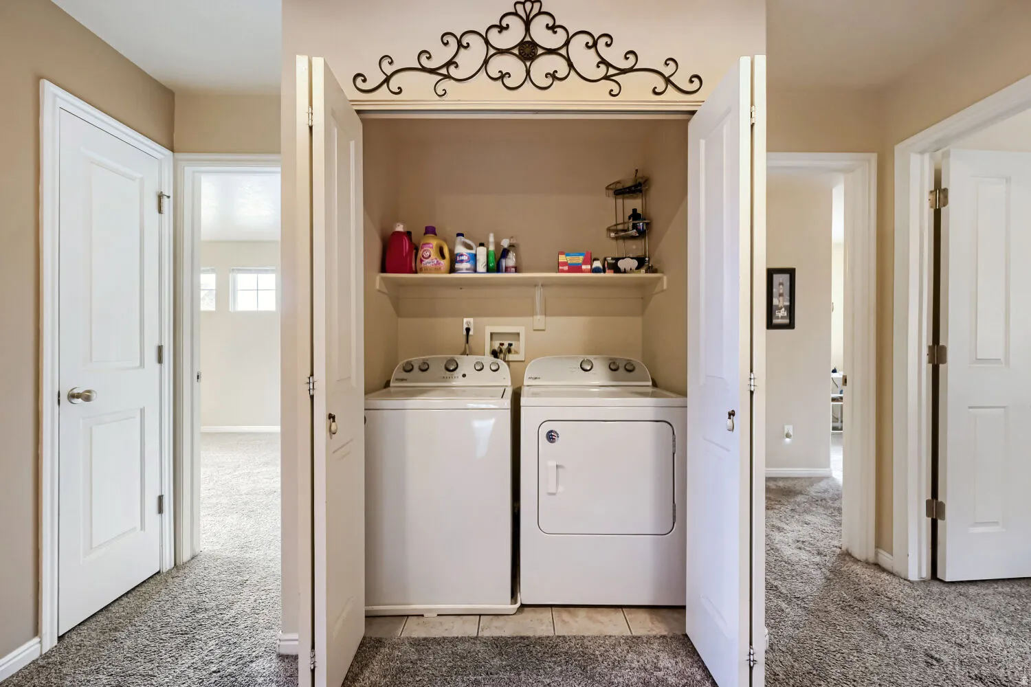 Laundry closet with bi-fold doors, white shelving, and tile flooring