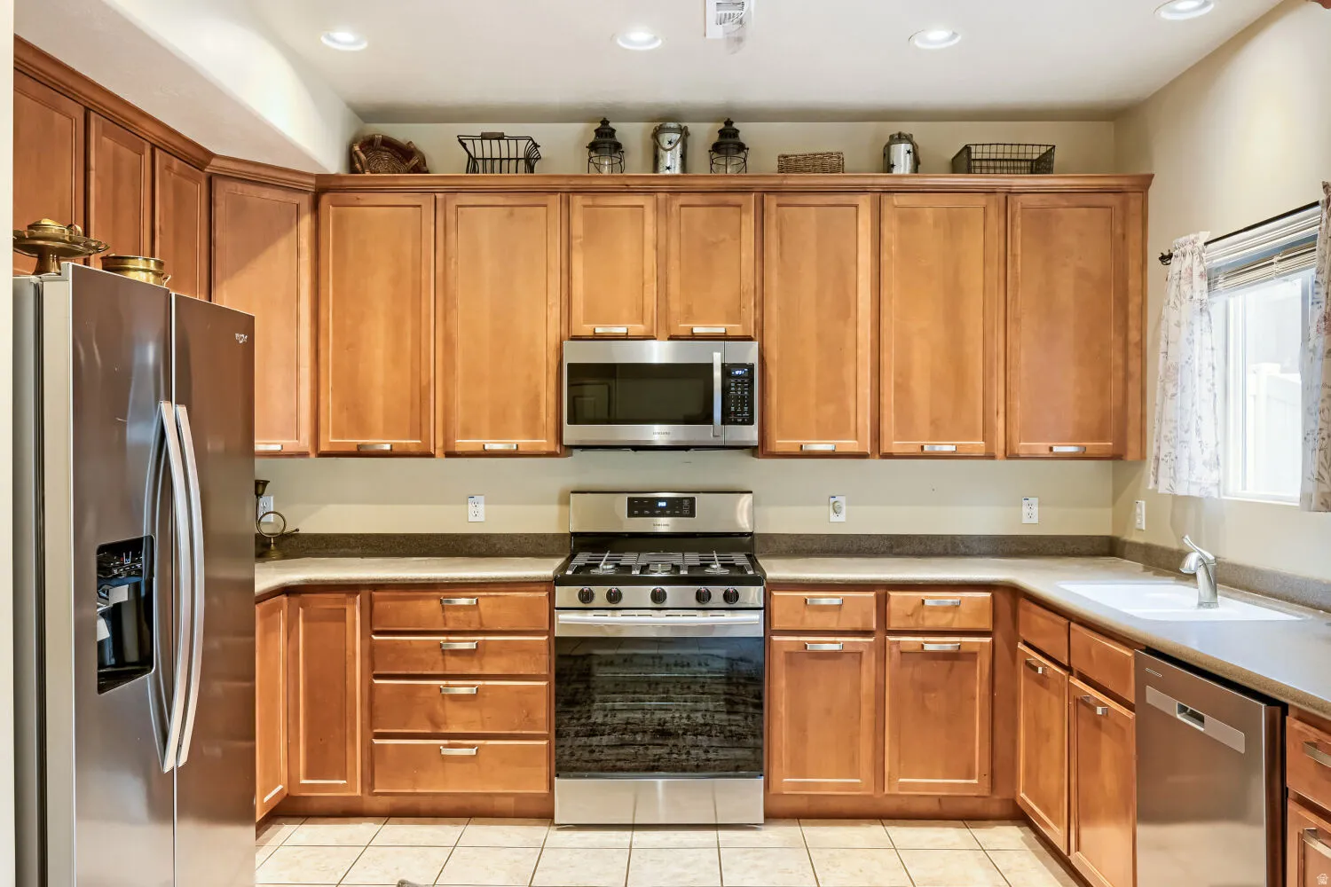Stainless steel appliances, recessed lighting, wood cabinetry, built-in microwave, and a gas range