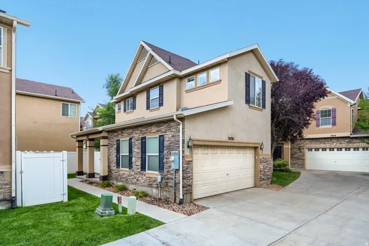 Detached two-story home with covered front porch, stone accents and 2-car garage