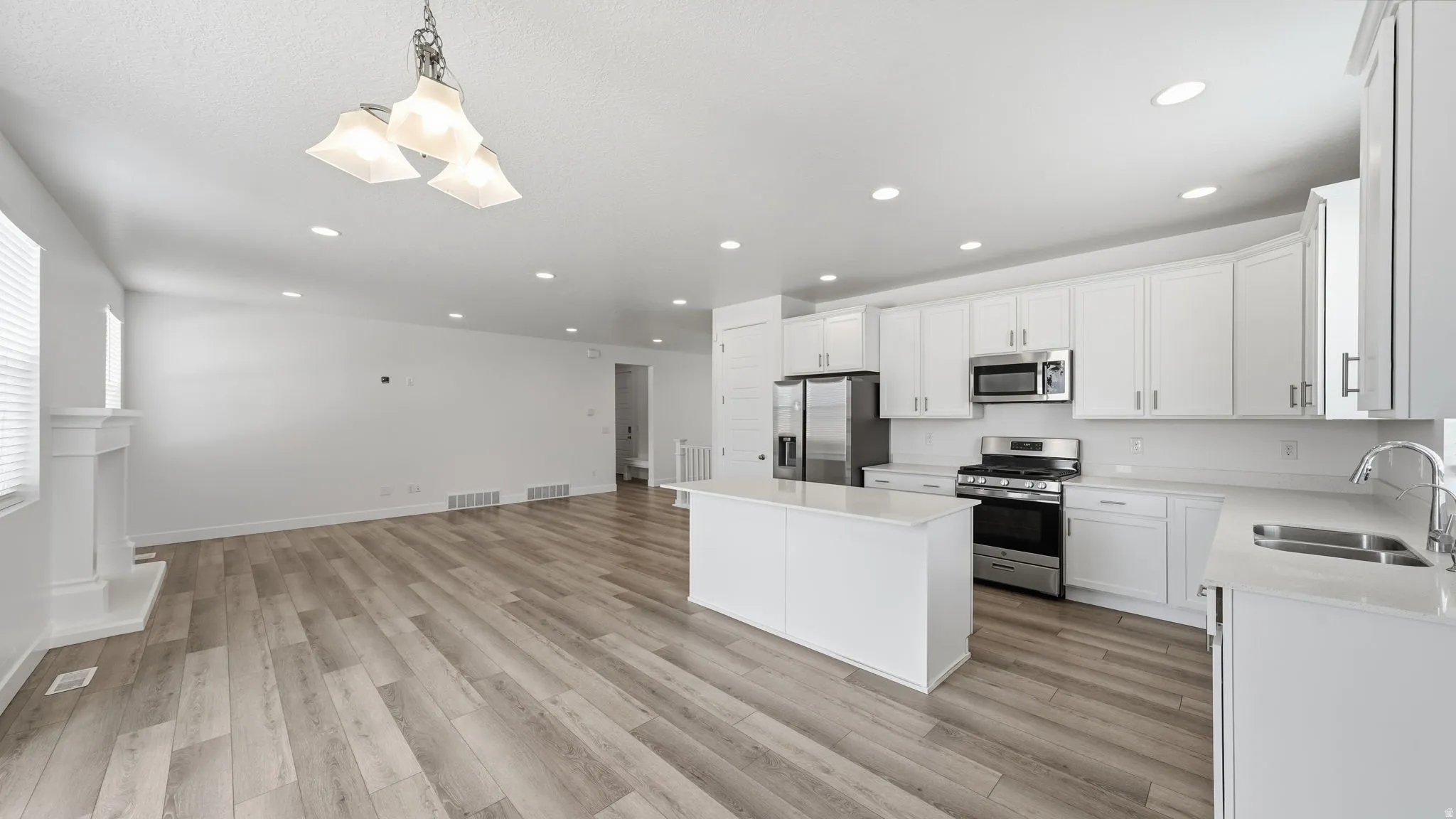 Kitchen featuring a center island, stainless steel appliances, white cabinetry, and light-toned countertops