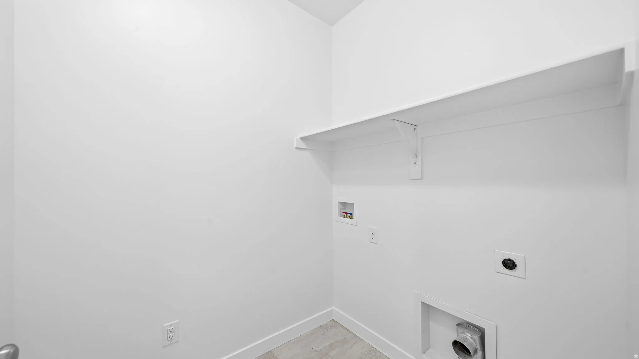Laundry area with built-in shelving, white walls, and light-toned flooring