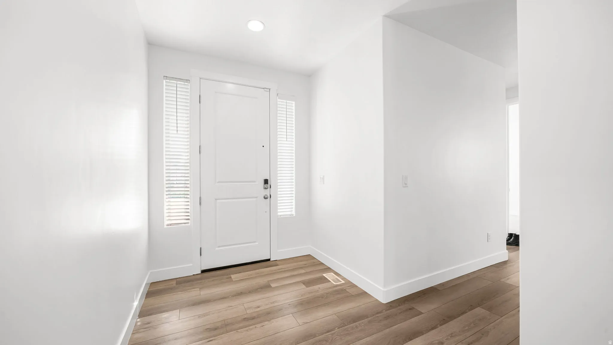 Entryway featuring a solid panel door with sidelights, wood-finish flooring, and recessed lighting