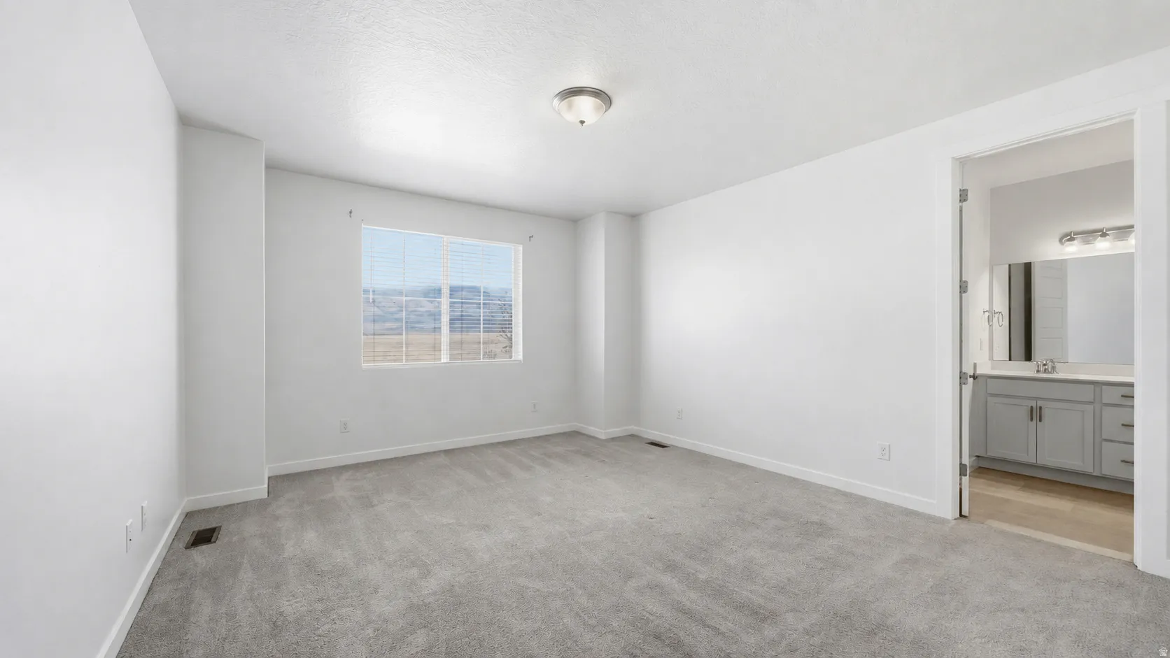 Spacious Owner's bedroom with added bump-out, cream colored carpeting, neutral white walls, and a ceiling-mounted light fixture