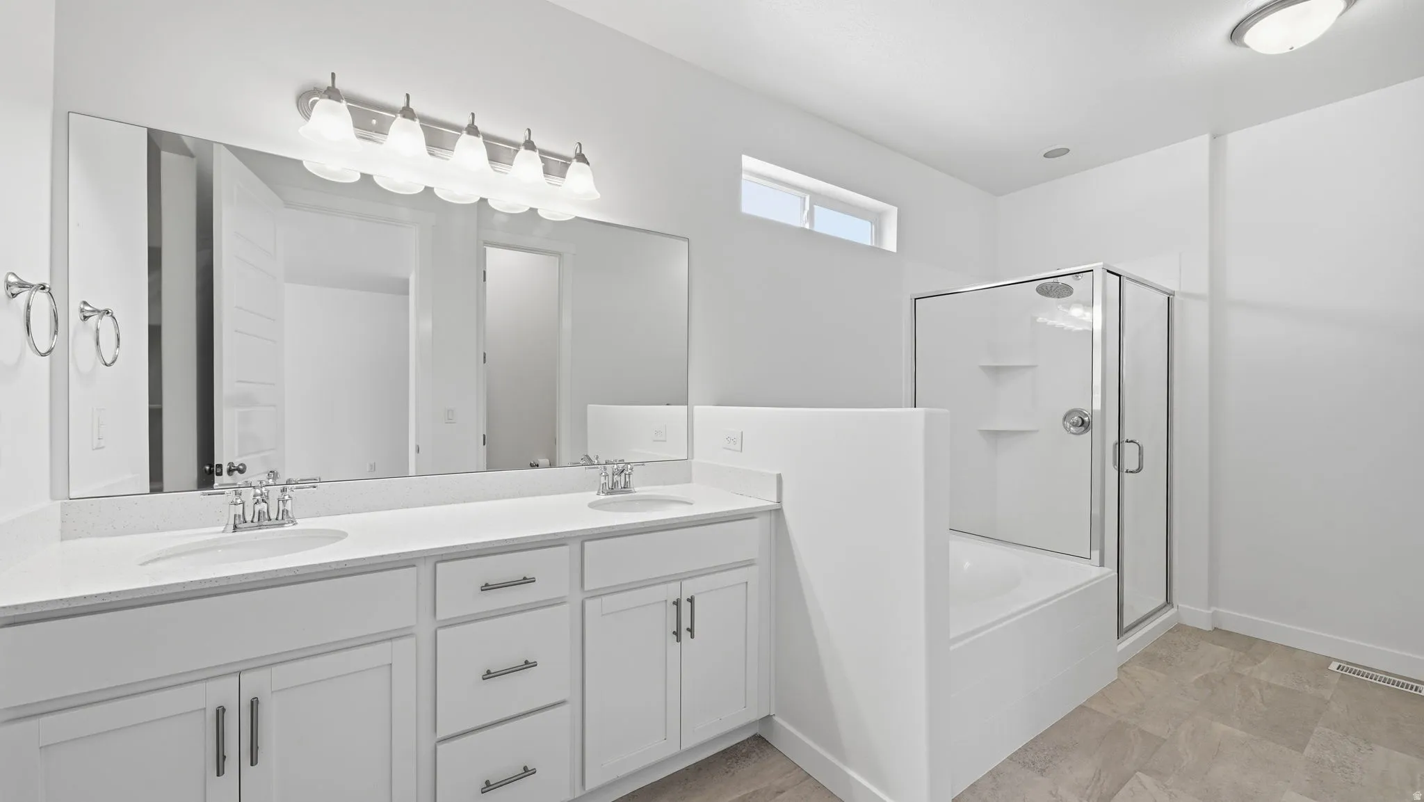 Double vanity with white cabinetry, polished chrome fixtures, soaker tub and separate shower