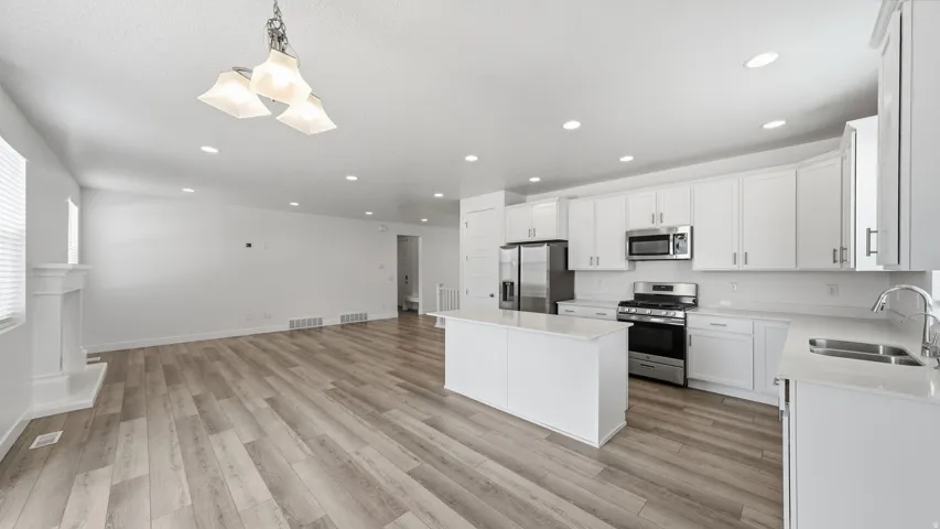 Kitchen featuring a center island, stainless steel appliances, white cabinetry, and light-toned countertops