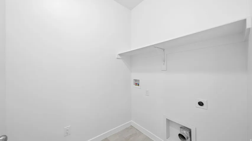 Laundry area with built-in shelving, white walls, and light-toned flooring
