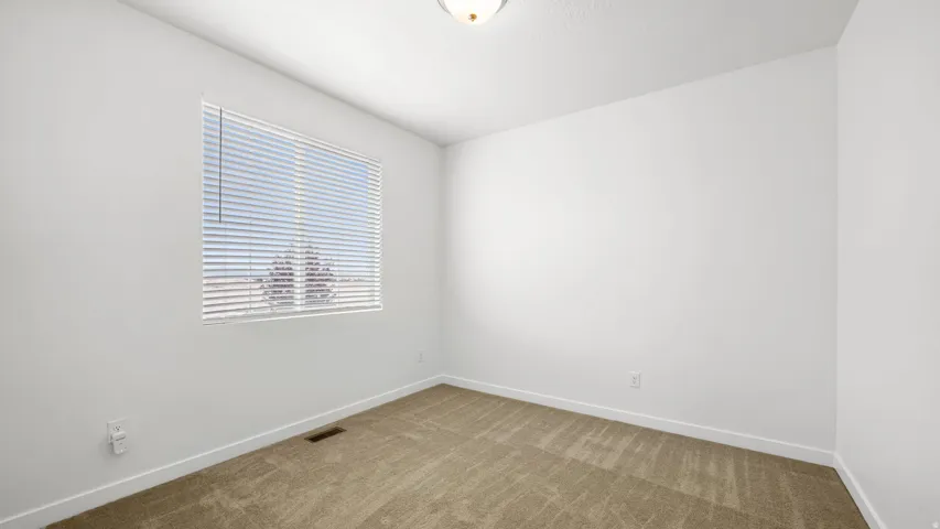 Neutral wall color, carpeted flooring, and a flush-mount ceiling light