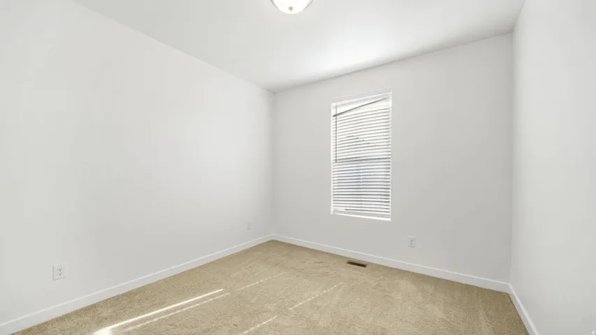 Neutral wall finish, carpeted flooring, window with horizontal blinds, and a flush mount ceiling light fixture