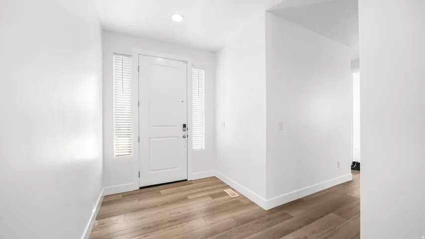 Entryway featuring a solid panel door with sidelights, wood-finish flooring, and recessed lighting