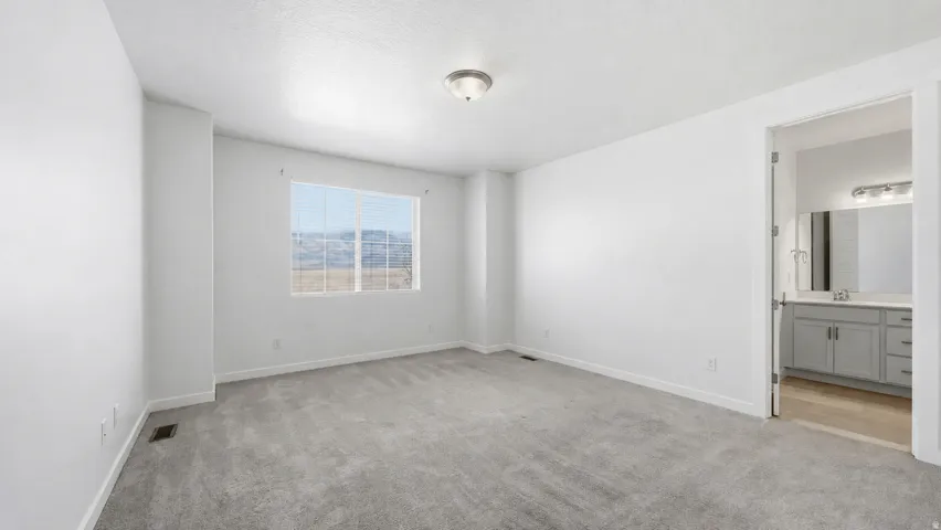 Spacious Owner's bedroom with added bump-out, cream colored carpeting, neutral white walls, and a ceiling-mounted light fixture