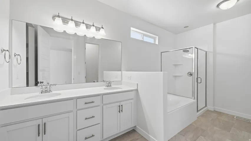 Double vanity with white cabinetry, polished chrome fixtures, soaker tub and separate shower