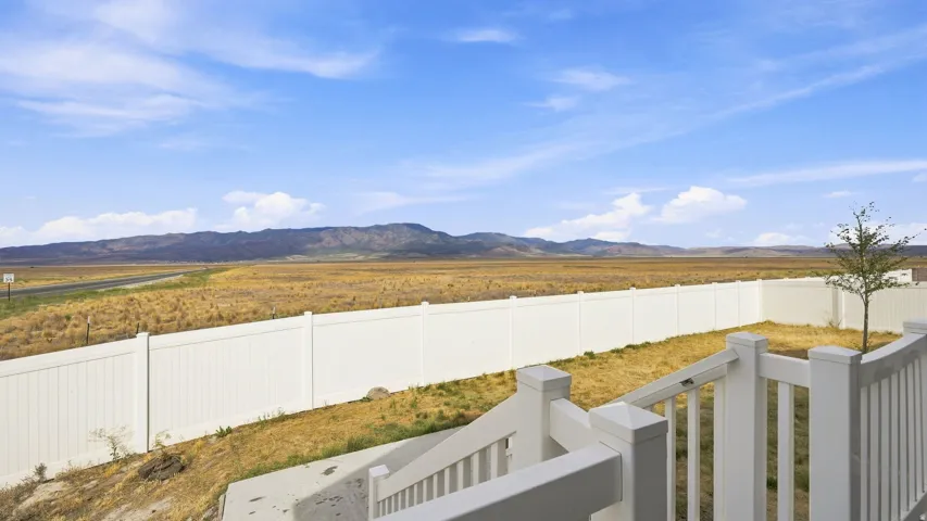 Exterior deck with white railings, private fenced backyard, and a beautiful mountain landscape