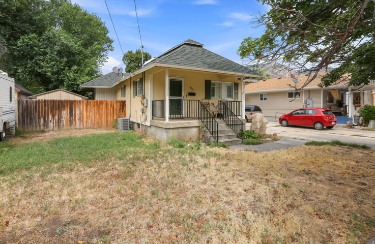 Single-story residence with a covered porch, exterior stairs with metal railings, and a wood privacy fence