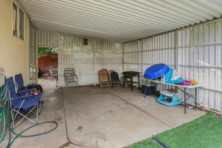 Covered patio area featuring a concrete slab floor, corrugated metal roof, and partial corrugated metal walls