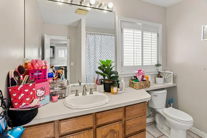 Bathroom featuring a vanity with an integrated sink, wood-finish cabinetry, and a window with plantation shutters