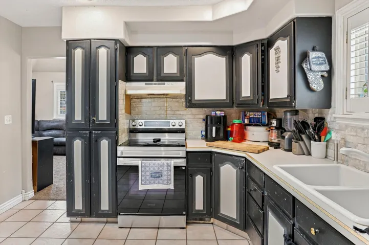 Kitchen featuring dark-finished cabinetry, white countertops, tile flooring, a stainless steel range, and a dual basin sink