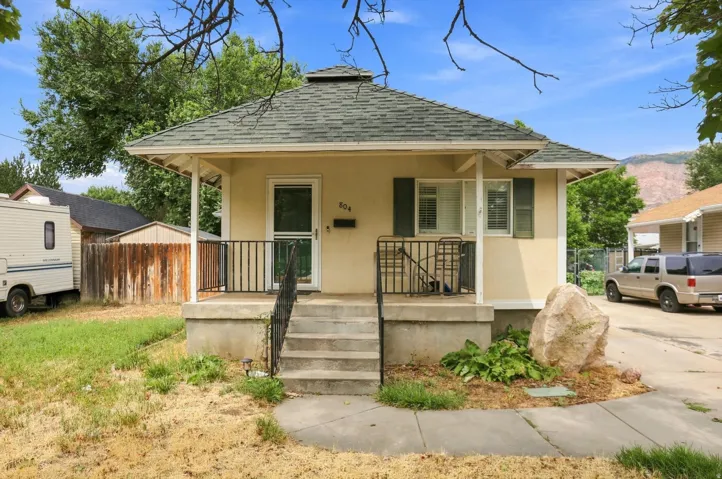 Single-story residence featuring a covered front porch, concrete steps, and a decorative rock