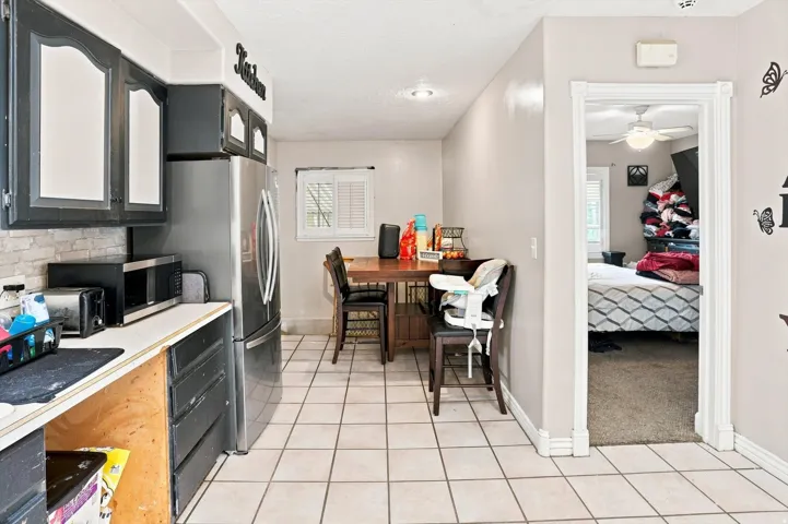 Kitchen featuring tile flooring, painted cabinetry, and a window with horizontal blinds