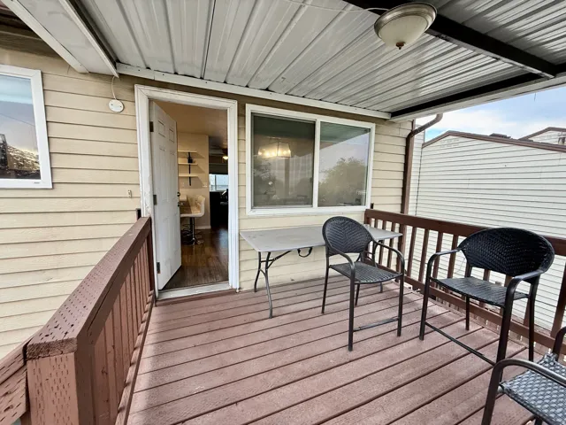 Covered outdoor deck with wood-finish flooring, wood railing, and vinyl siding