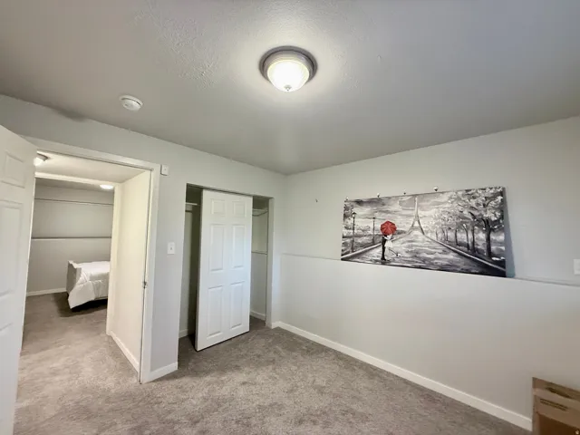 Light gray wall paint, textured ceiling, and gray carpeted flooring