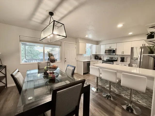 Open-concept living space featuring a modern kitchen with stainless steel appliances, white cabinetry, and a central island with bar seating