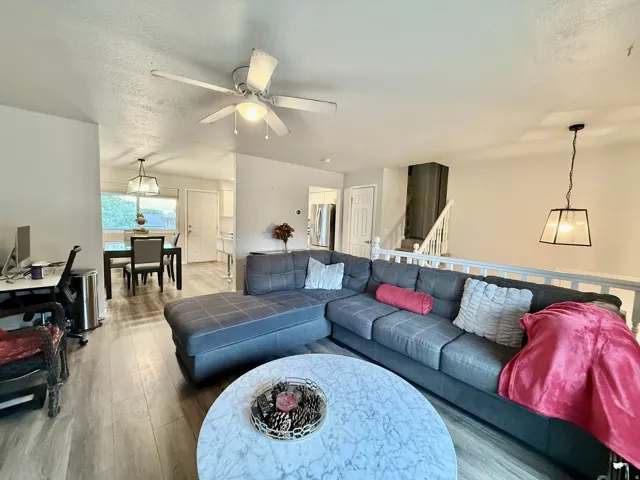 Wood-finish flooring throughout, ceiling fan with integrated lighting, recessed lighting, and a contemporary pendant light fixture