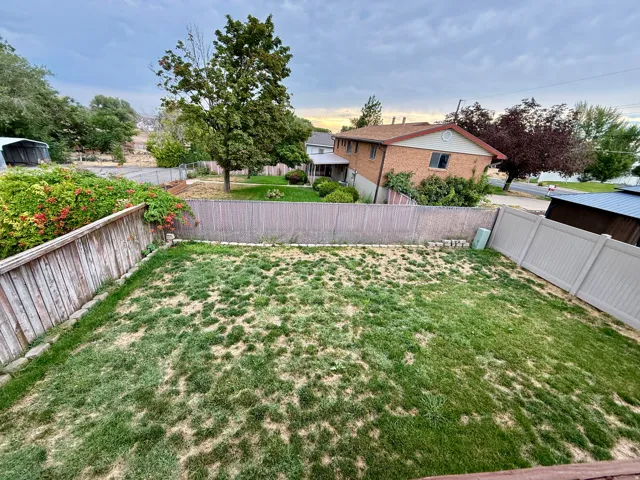 Expansive outdoor space featuring a wood fence, vinyl fence, and established trees