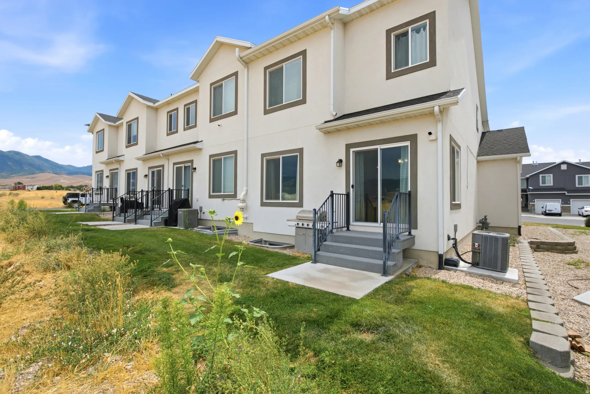 Rear exterior featuring multiple sliding glass doors, dedicated patios, and air conditioning units