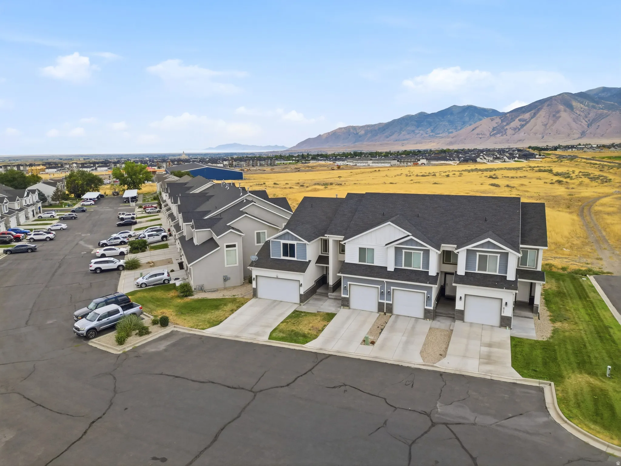 Row of attached residential units featuring individual garage entries and gray shingle roofing