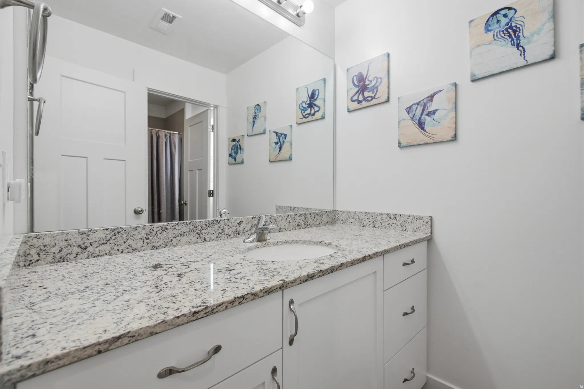 White vanity with integrated sink, granite countertop, and silver-tone hardware