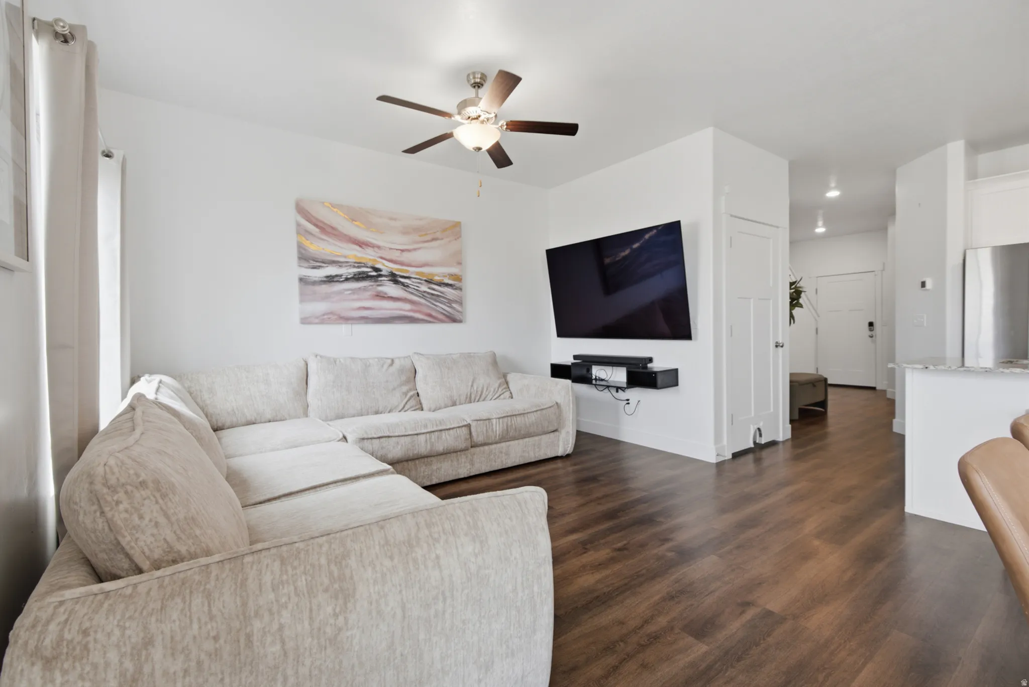 Wood-finish flooring throughout, bright white walls, and a ceiling fan with integrated lighting
