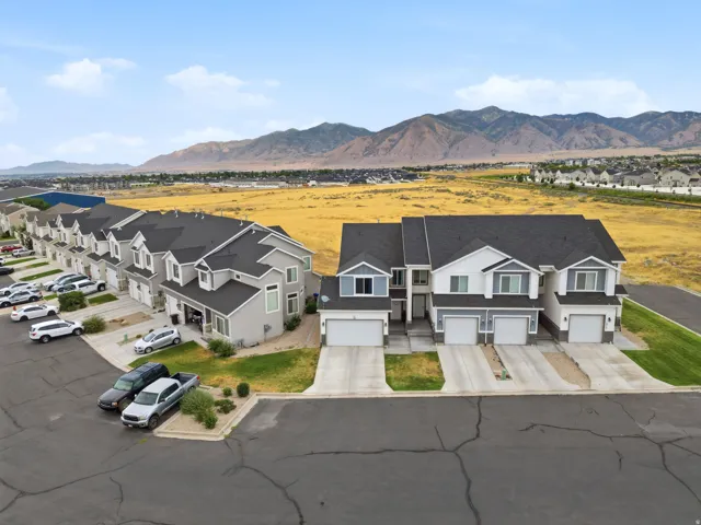Row of townhomes featuring attached garages, paved driveways, and mountain scenery