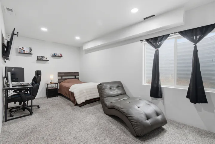 Recessed lighting illuminates the room, featuring light gray carpeting