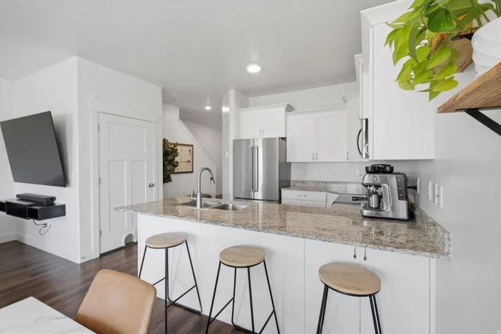 Kitchen featuring white cabinetry, a large island with a sink, stainless steel appliances, and wood-finish flooring
