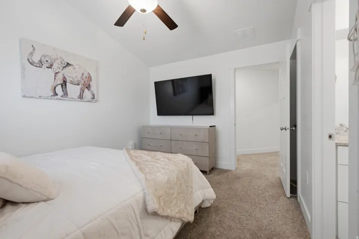 Neutral wall color, angled ceiling, built-in ceiling fan, neutral carpet, and a white interior door with a silver-tone knob