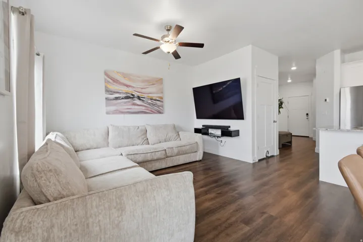 Wood-finish flooring throughout, bright white walls, and a ceiling fan with integrated lighting