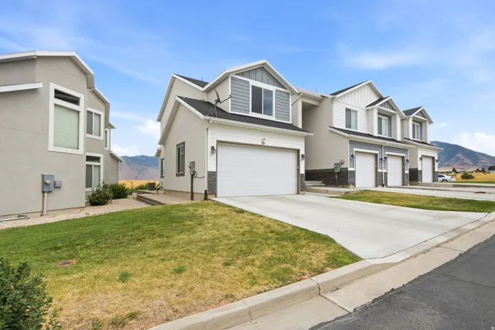 Two-story exterior with a combination of siding and stone veneer, attached single-car garage, and concrete driveway