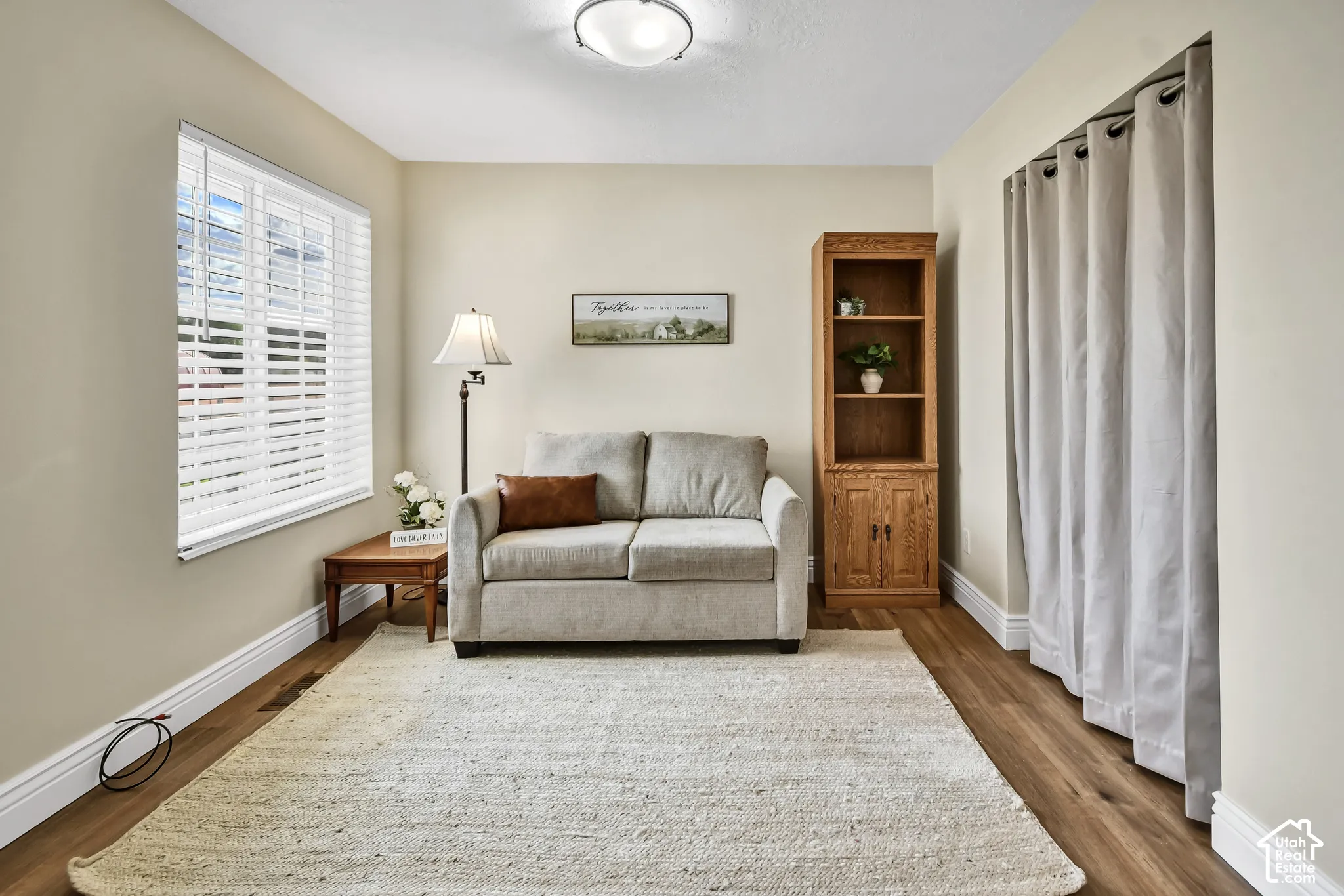 Hardwood-style flooring, white window blinds, and a built-in light fixture
