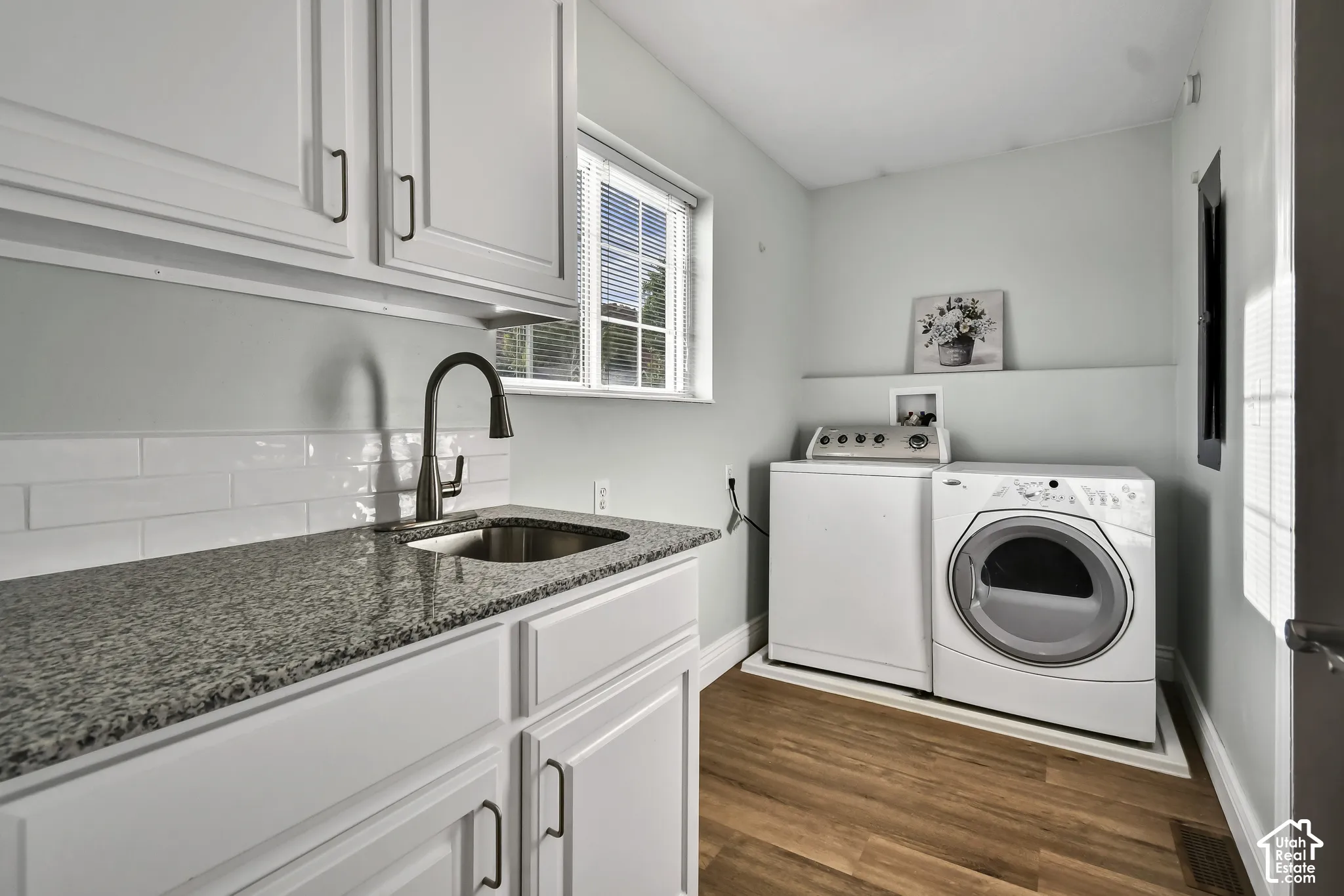 White cabinetry, granite-style countertop, undermount sink, matte black gooseneck faucet, and wood-finish flooring