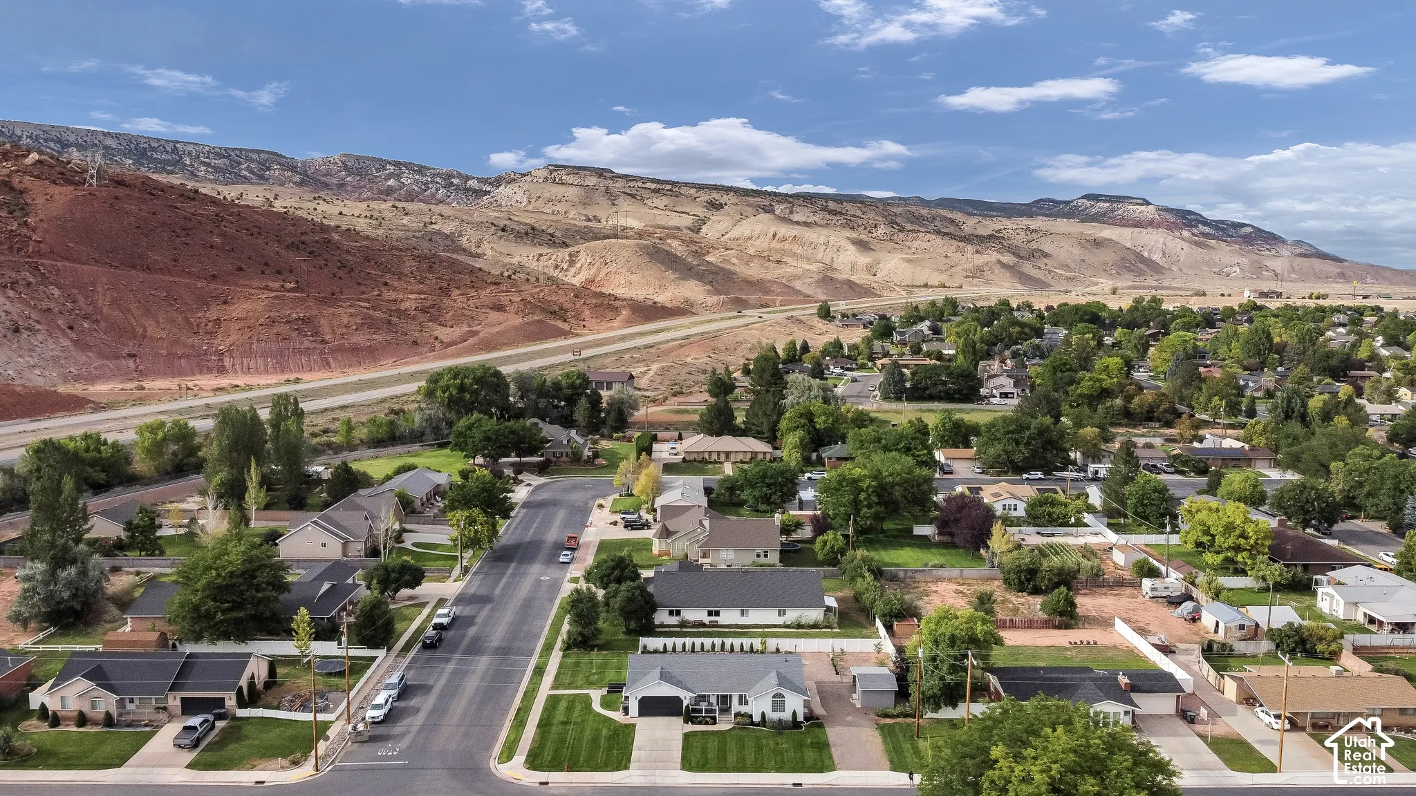Residential neighborhood with paved streets and mature trees, set against a backdrop of distant mountains