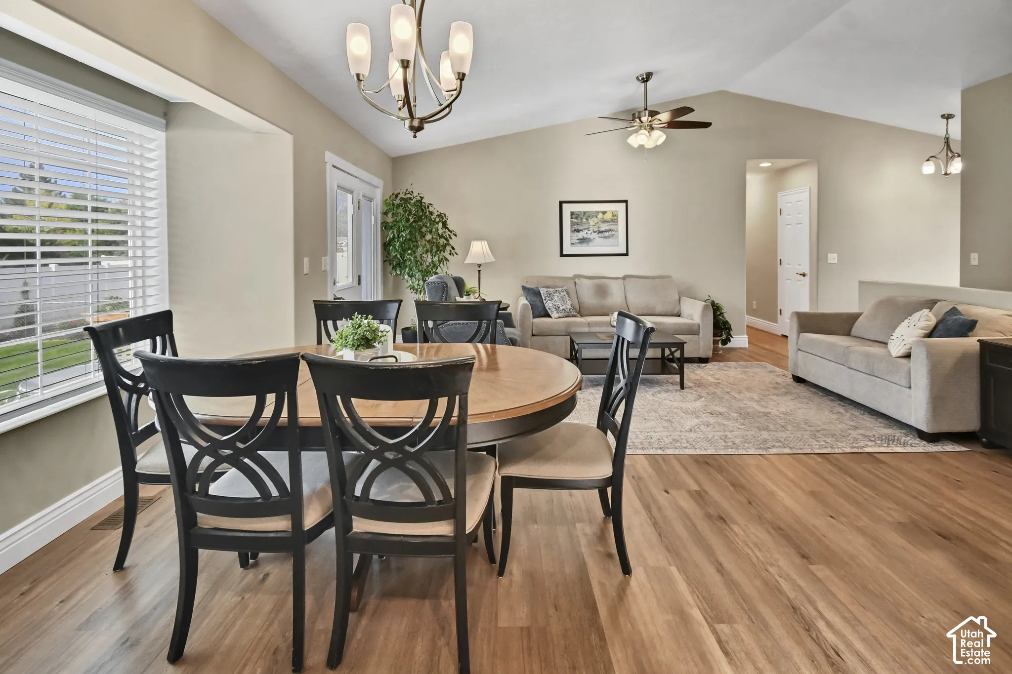 Vaulted ceilings with a ceiling fan, wood-finish flooring, bay window, and a chandelier lighting fixture