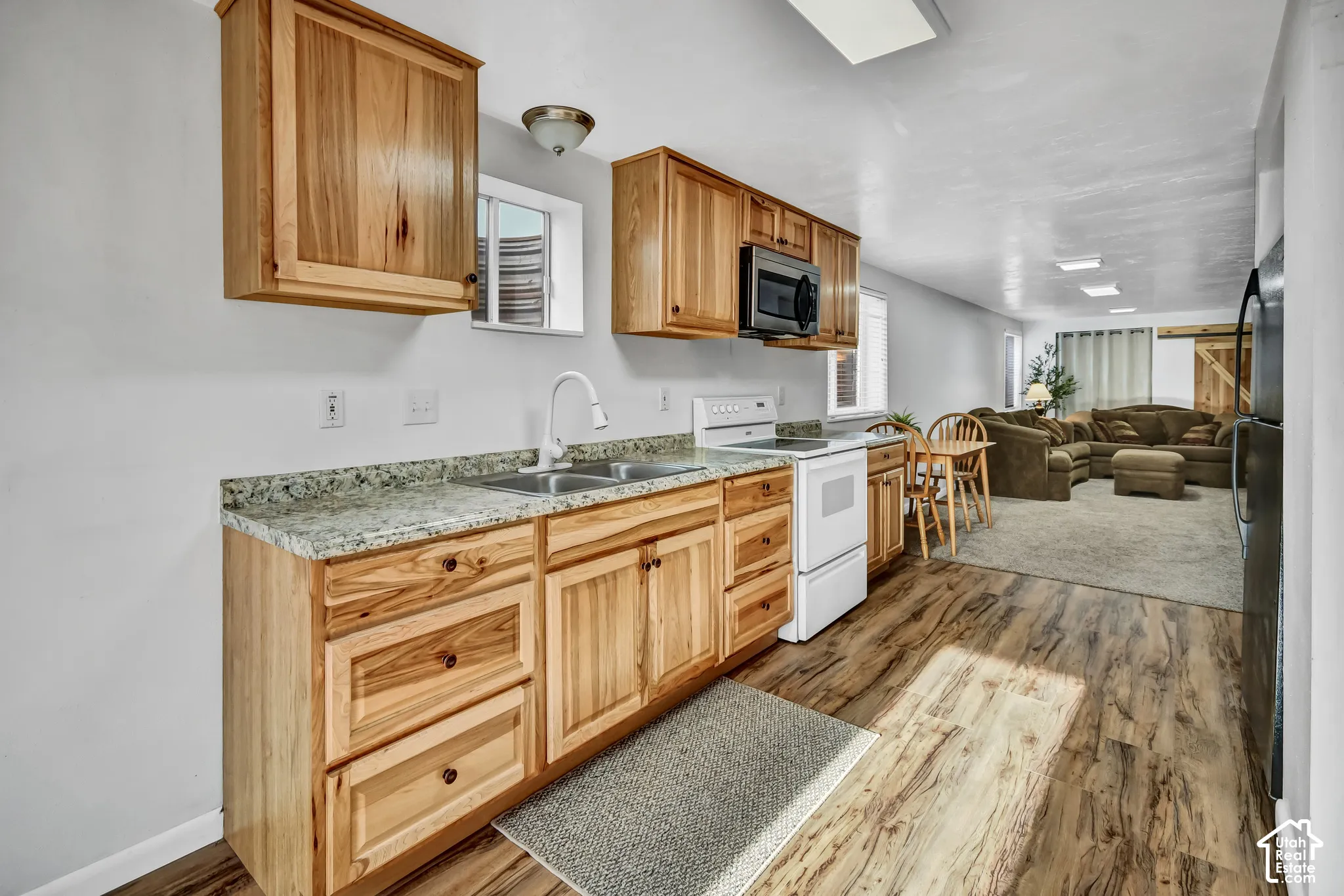 Wood-finish flooring with light wood cabinetry, stone-look countertops, and stainless steel sink