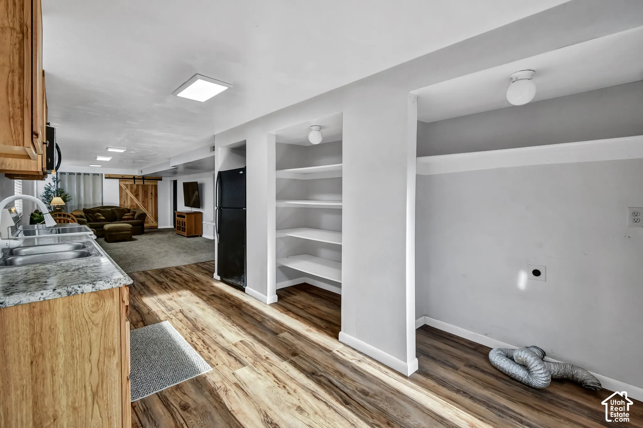 Wood-finish flooring, built-in shelving, recessed ceiling lighting, granite-style countertops, and a barn-style door
