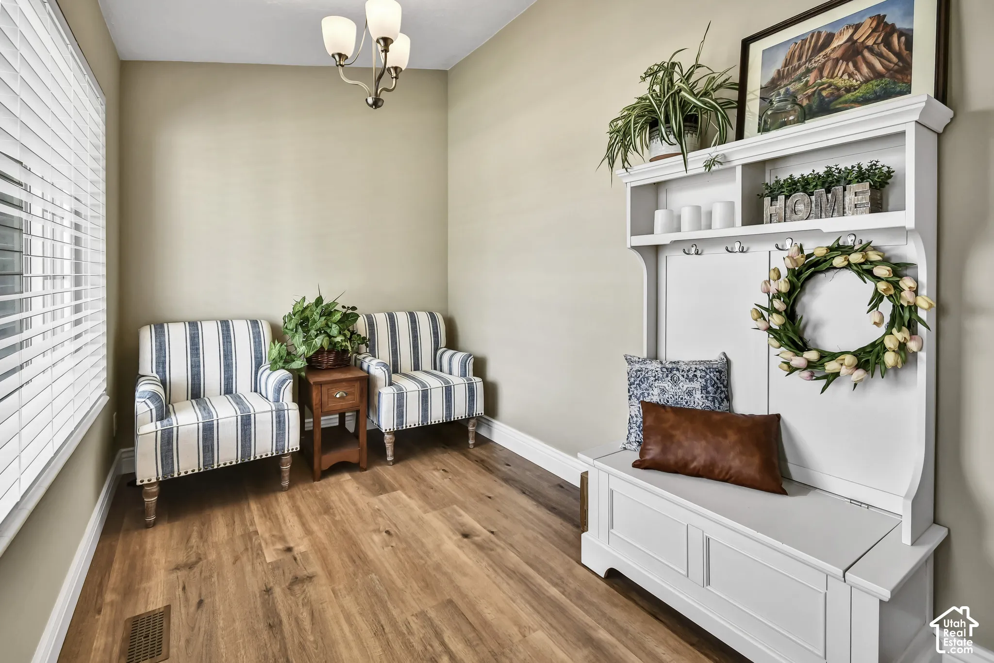 Warm wood-finish flooring, a contemporary white built-in storage bench, and a modern three-light chandelier