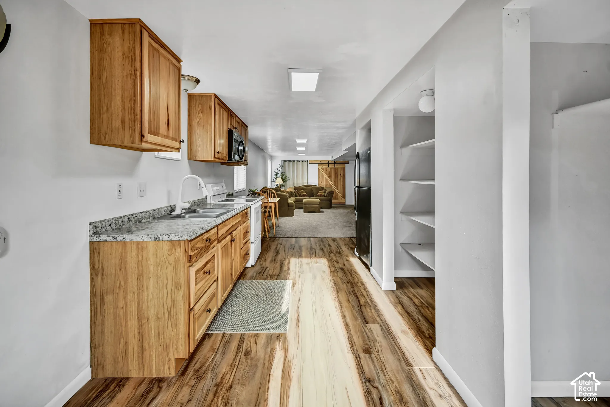 Wood-finish flooring throughout, wood cabinetry, granite-style countertops, white kitchen appliances, and built-in shelving