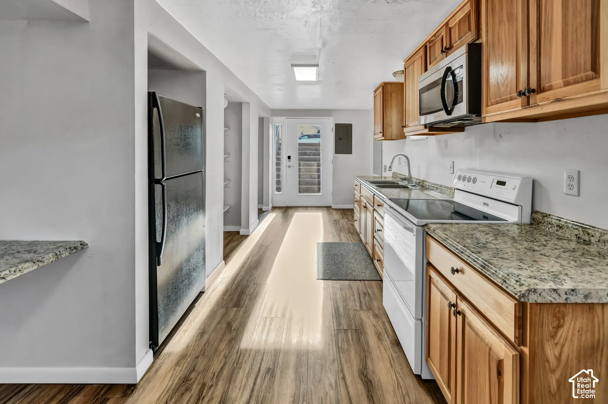 Kitchen featuring wood-finish flooring, light-toned cabinetry, granite-finish countertops, and stainless steel appliances